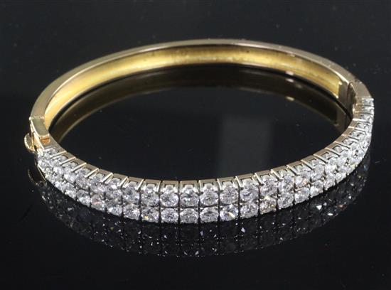 A gold and double row channel set diamond hinged bangle,